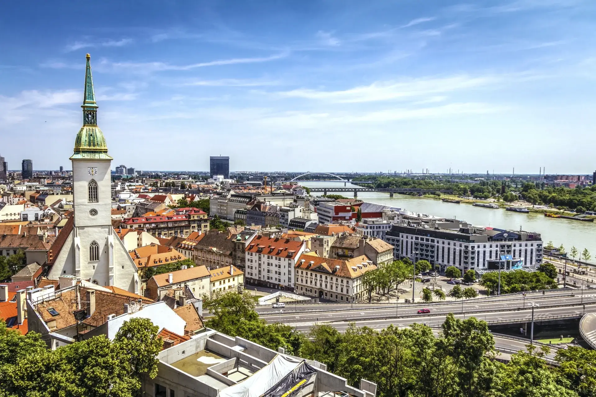 Udsigt over Bratislava, Slovakiets hovedstad, med Sankt Martins Katedral i forgrunden og Donau-floden i baggrunden.