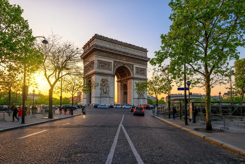Triumfbuen i Paris ved solnedgang med allé og trafik