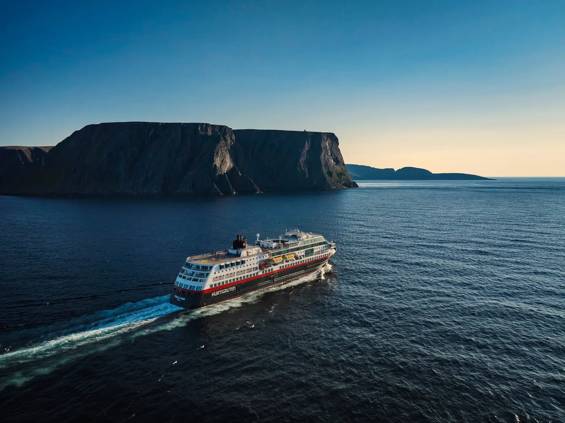 Hurtigruten-skib på åbent hav i aftenlys — tog og skib kombineret