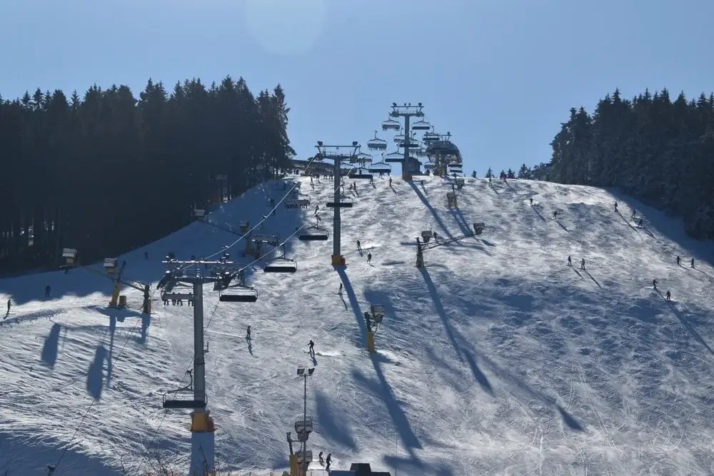 Bred piste med skilift og mange skiløbere på vej ned
