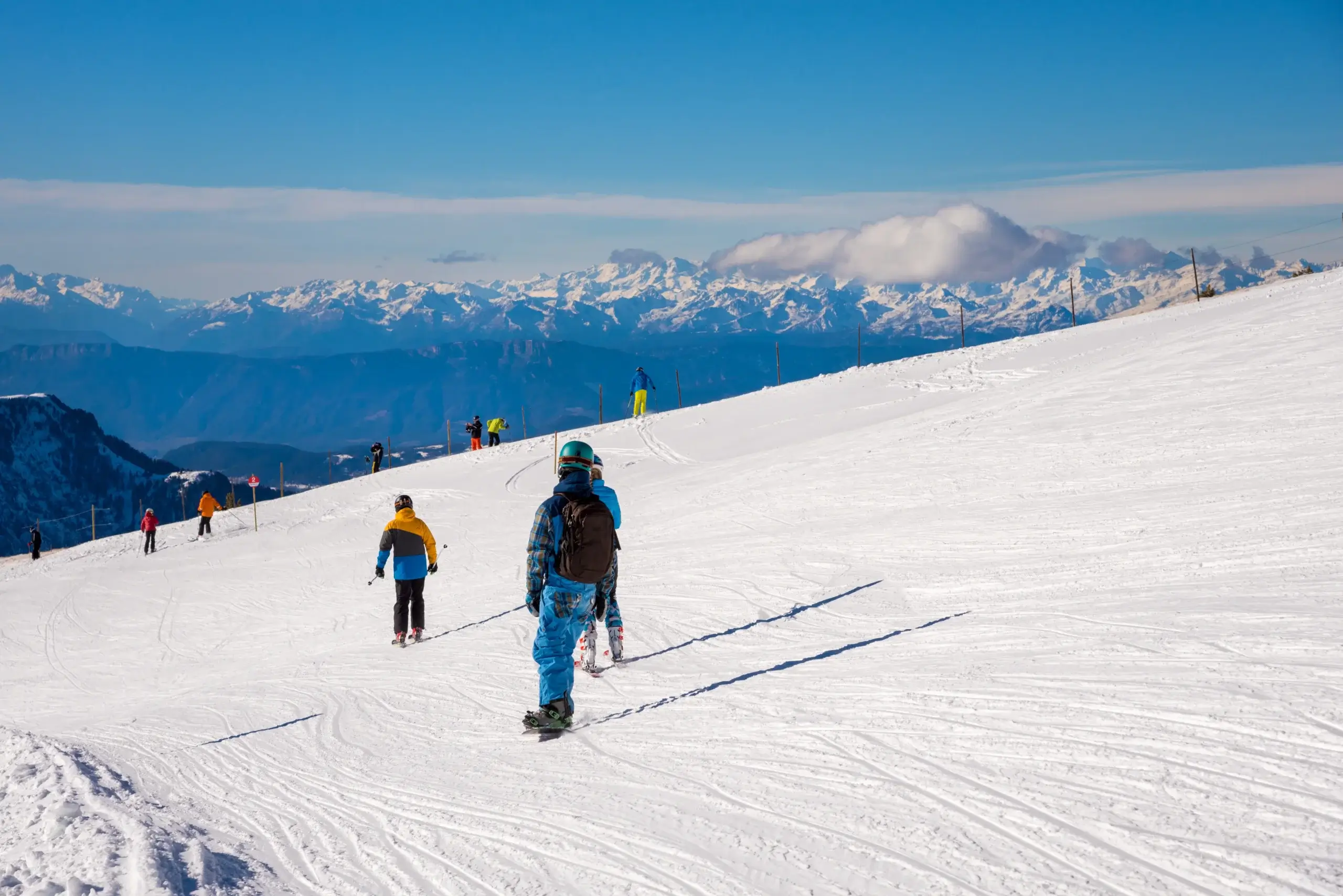 Skiløbere på en bred piste med udsigt til Dolomitternes tinder