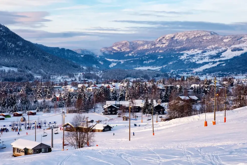 Skiområde ved solnedgang med landsby og pister i sneen
